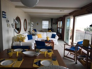 A dining area with a table set for four, a white sofa, and a large window with a view.