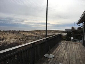 A wooden deck with a metal railing overlooking a sandy beach and dunes. - Sought after LEYC oceanfront (Beach Haven)