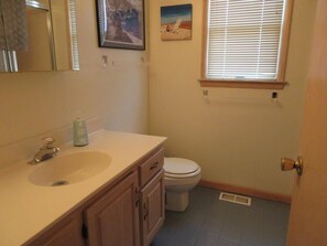 Bathroom features a sink, toilet, and window with blinds.