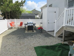 Enjoy al fresco dining on the patio, where a barbecue grill and table await, surrounded by lush trees and a deck.