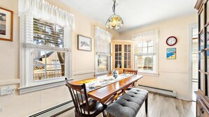 Une salle à manger avec une table en bois, des chaises, un banc et un lustre.