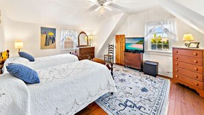 Une chambre à coucher avec un lit, une commode, une télévision et une vue sur l’extérieur.