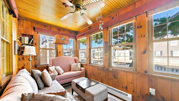 L’intérieur d’un chalet accueillant, avec un plafond en bois, de grandes fenêtres, un canapé, une table basse et une cheminée.