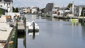 Ein Yachthafen am Wasser mit vertäuten Booten, hölzernen Stegen und Gebäuden im Hintergrund.