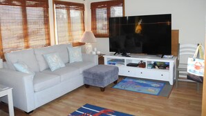 Ein Wohnzimmer mit Sofa, Fernseher und einem kleinen Tisch.