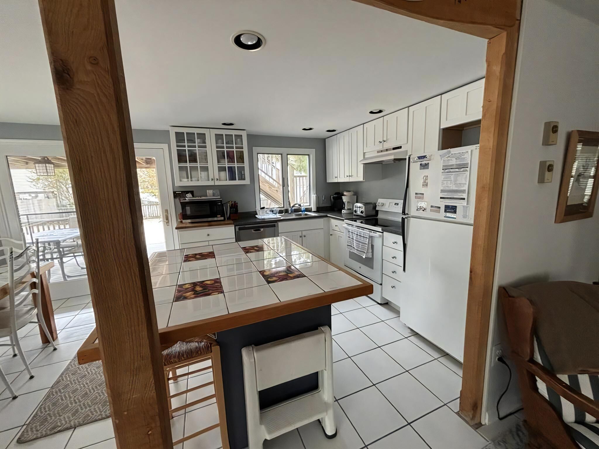 A modern kitchen with white cabinets, a tiled backsplash, and a central island with stools.
