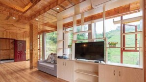 A wooden interior with a TV, sofa, and large windows overlooking a green landscape. - Longji Rice Terraces Heshe Homestay (Longsheng)