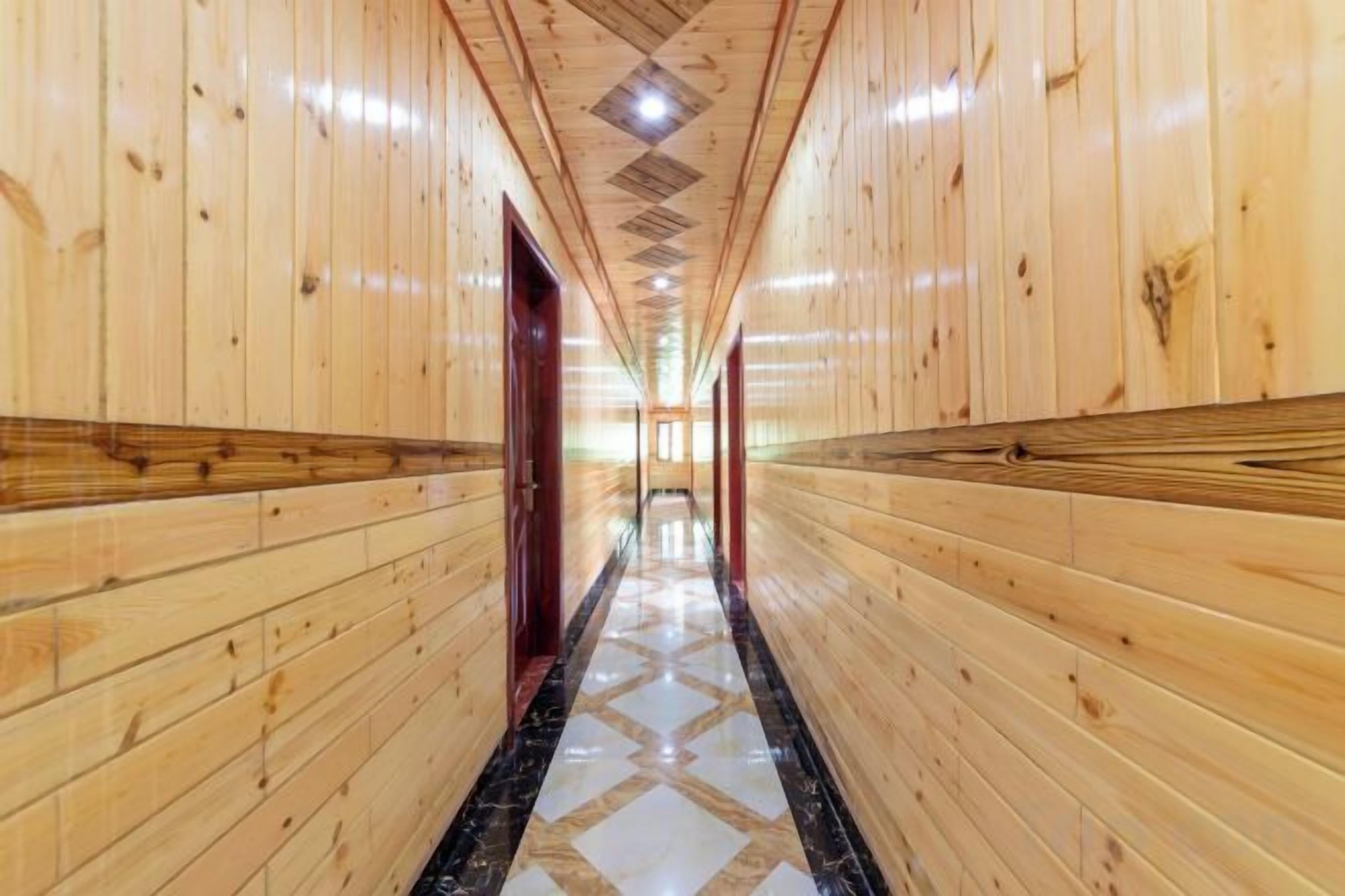A wooden hallway with a patterned floor, leading to a door at the end.