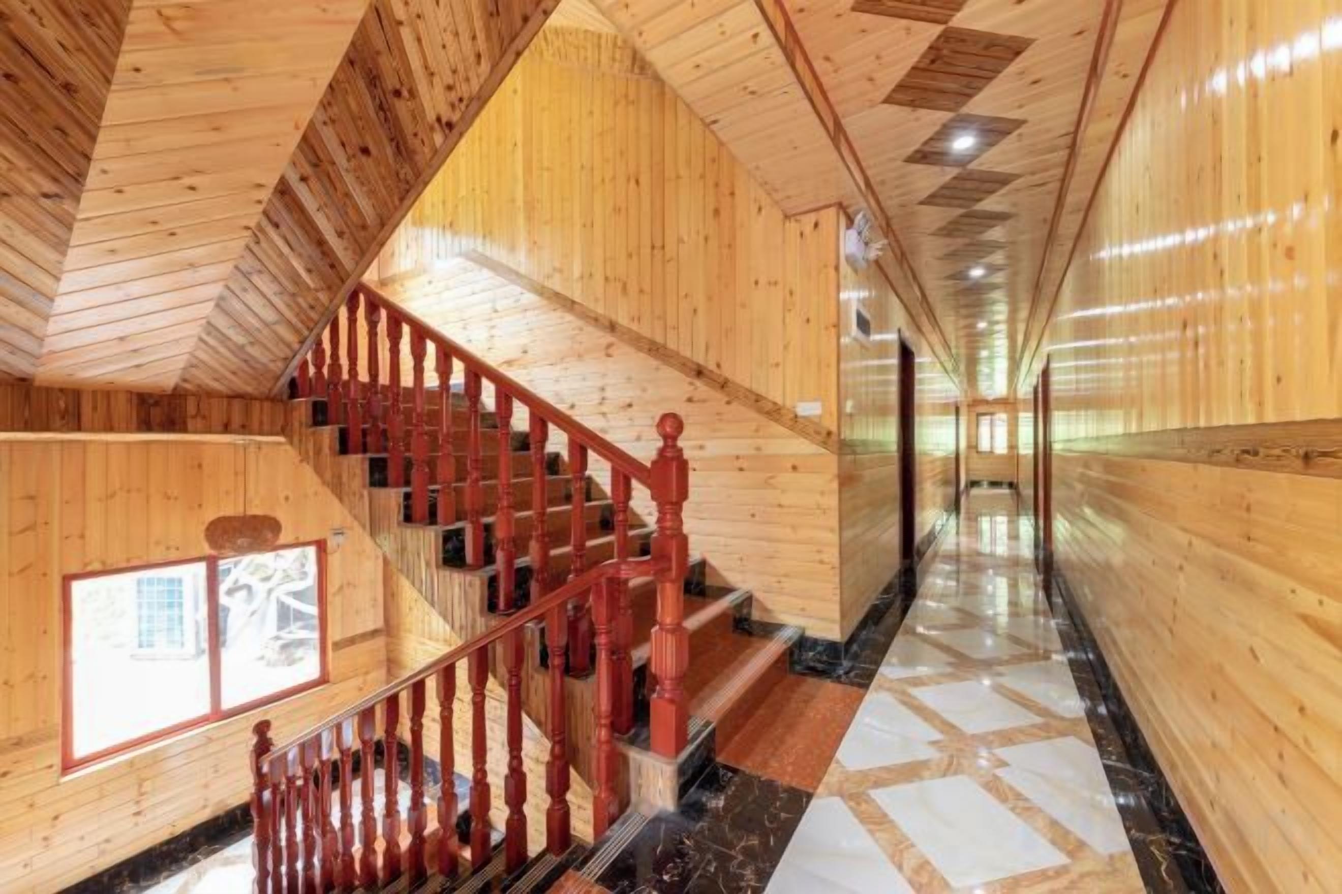 Un interior de madera con una escalera, un largo pasillo y un ventanal con vistas.