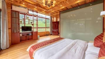 Un dormitorio espacioso con una cama grande, techo de madera y un televisor sobre un mueble de madera.