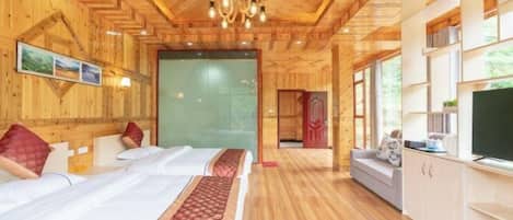 A wooden cabin-style room with a bed, a sofa, a TV, and a large window.