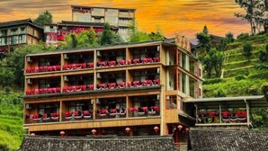 A multi-story building with balconies, surrounded by lush greenery. - Longji Rice Terraces Heshe Homestay (Longsheng)