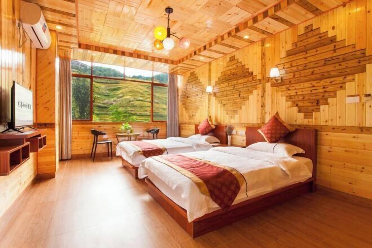 A wooden cabin-style room with two beds, a dining table, and a TV.