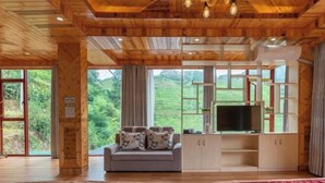 A wooden cabin with a sofa, TV, and two beds. - Longji Rice Terraces Heshe Homestay (Longsheng)
