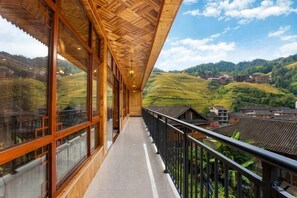 A balcony with a view of rolling hills and traditional buildings. - Longji Rice Terraces Heshe Homestay (Longsheng)
