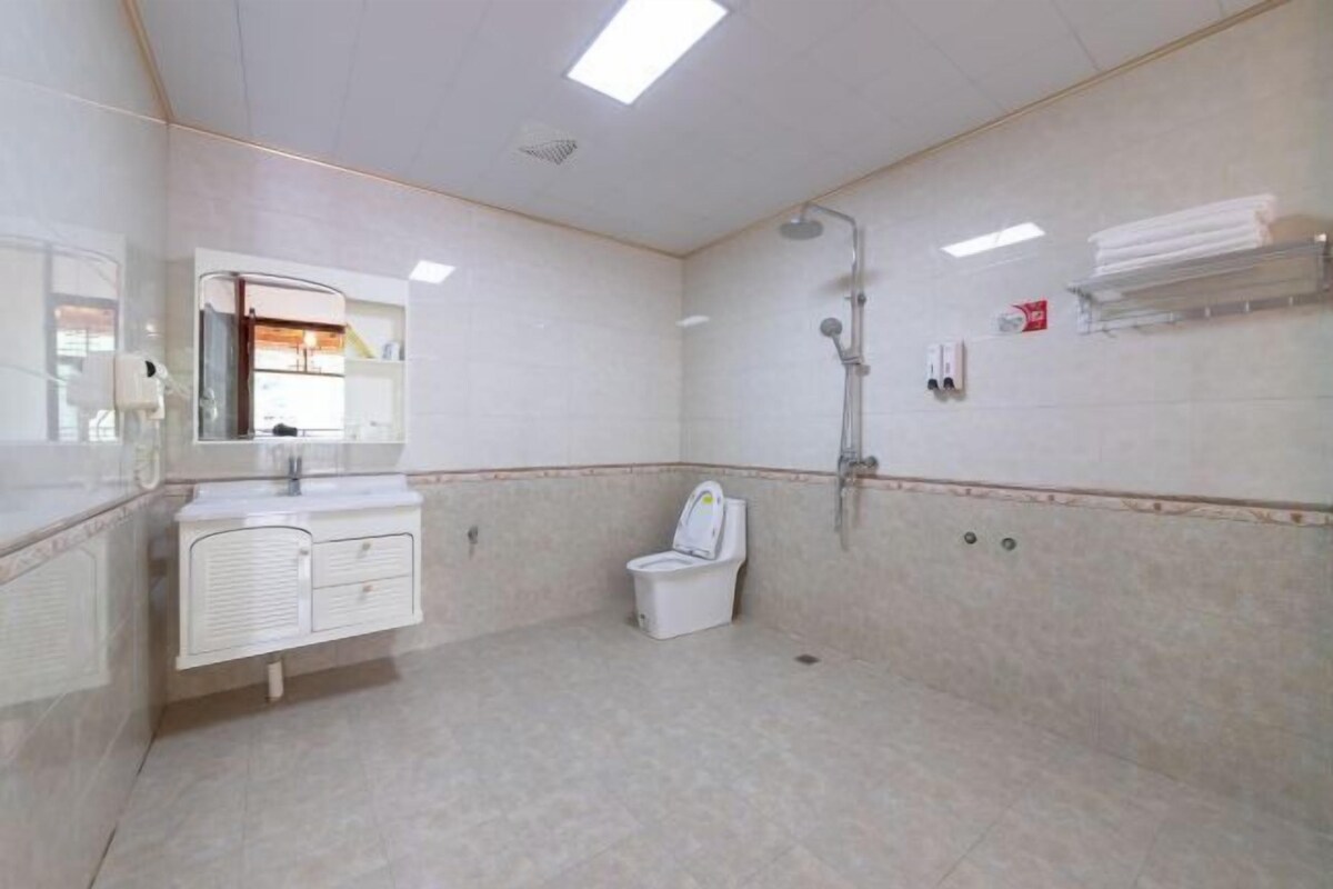 A bathroom with a toilet, shower, and a mirror above the sink.