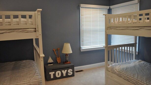 A room with two bunk beds, a small table with a lamp, a toy chest labeled "TOYS", and a window with blinds. - 5 bedroom accommodation in Loveladies (Loveladies)