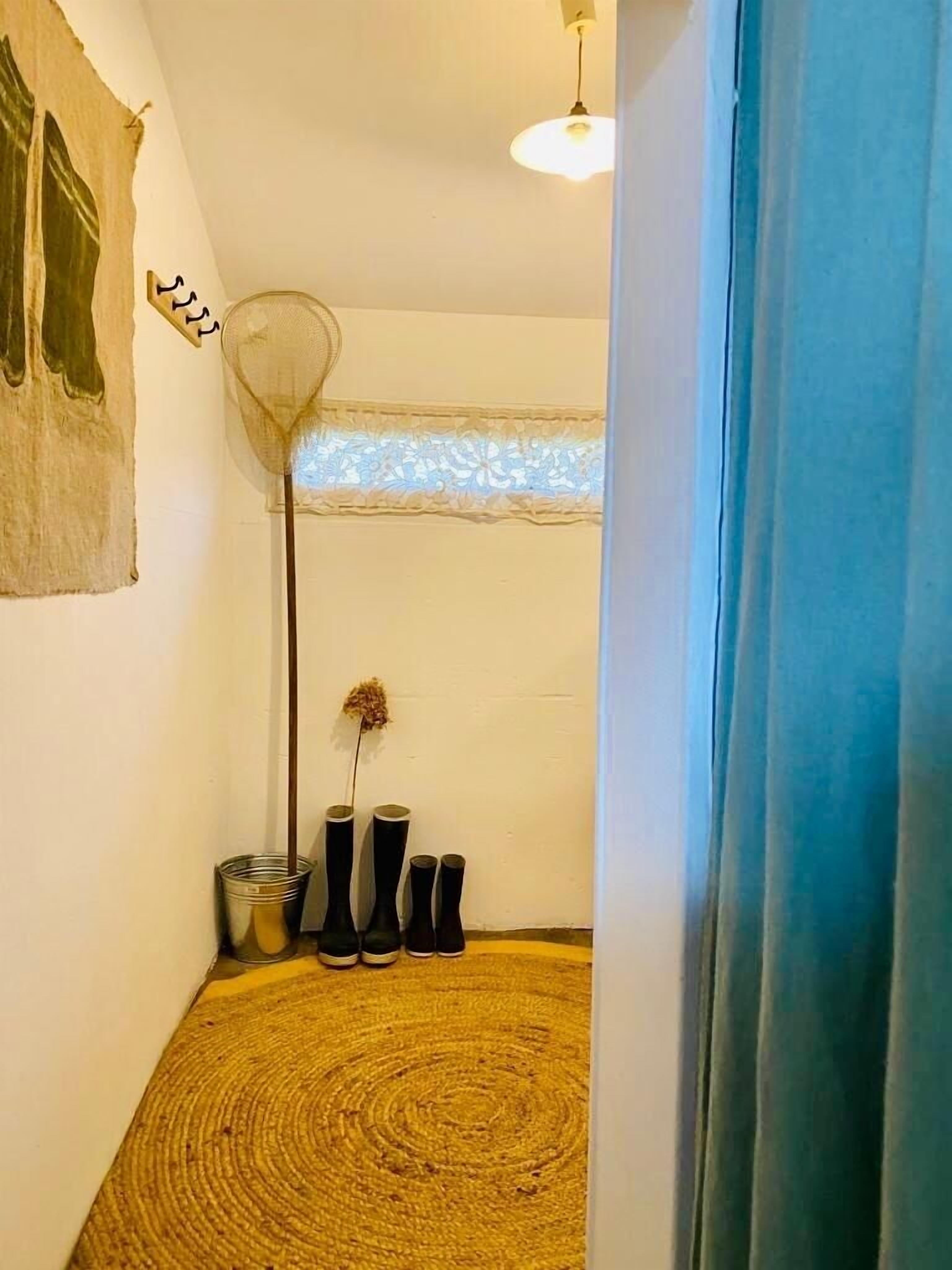 A narrow hallway with a patterned floor, a tall floor lamp, and a decorative wall piece.