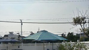 Un área junto a la piscina con mesas y sillas, una zona de estar cubierta y la piscina.