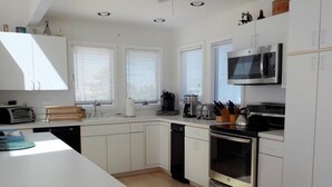 A modern kitchen with white cabinets, a stainless steel oven, a microwave, and a dishwasher. - OCEAN VIEWS! BEAUTIFUL HOME SLEEPS 14! (North Beach)