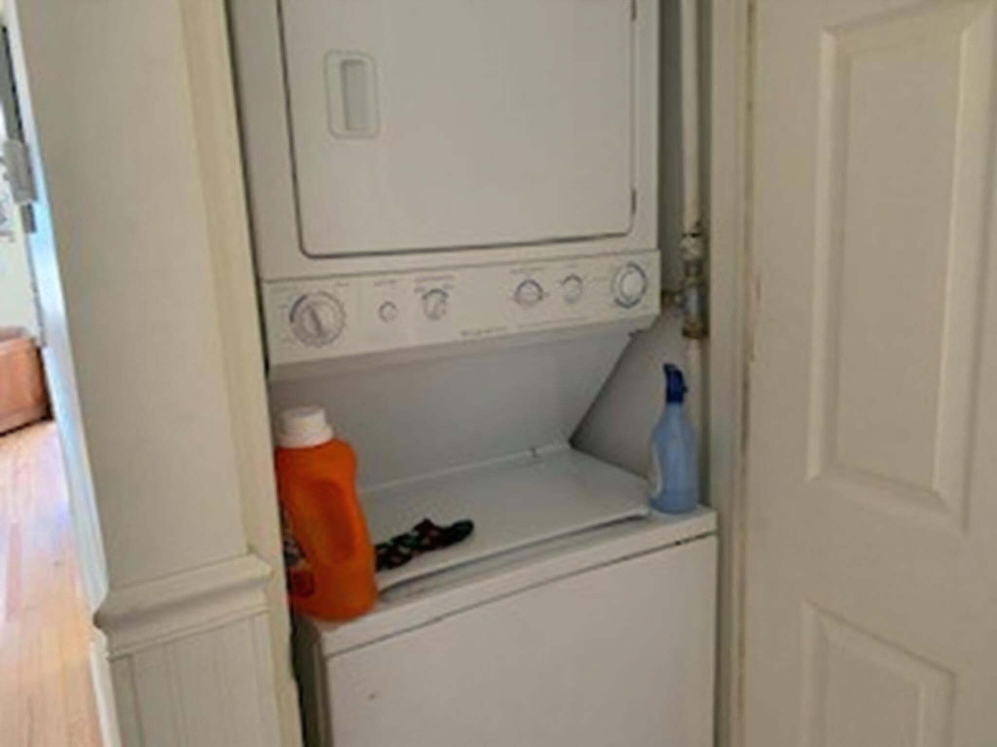 A white washing machine with a detergent bottle and a blue spray bottle on top.