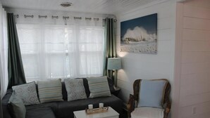 Una sala de estar con un sofá, una mesita con velas, una silla y un cuadro en la pared.