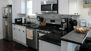 Una cocina moderna con armarios blancos, electrodomésticos de acero inoxidable y encimeras negras.