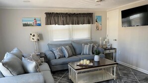 A living room with a sofa, a coffee table, and a lamp. - Newly renovated duplex located on the ocean block in the heart of Surf City. (Surf City)