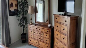 A room with a wooden dresser, a mirror, a television, a potted plant, and a framed picture on the wall. - Ship Bottom Ocean Block with Pool (Ship Bottom)