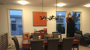Spisestue med et træbord, seks stole, en pendellampe og et indrammet kunstværk på væggen.