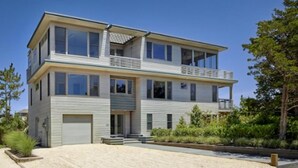 Et moderne hus i to etager med fladt tag, store vinduer og en balkon.