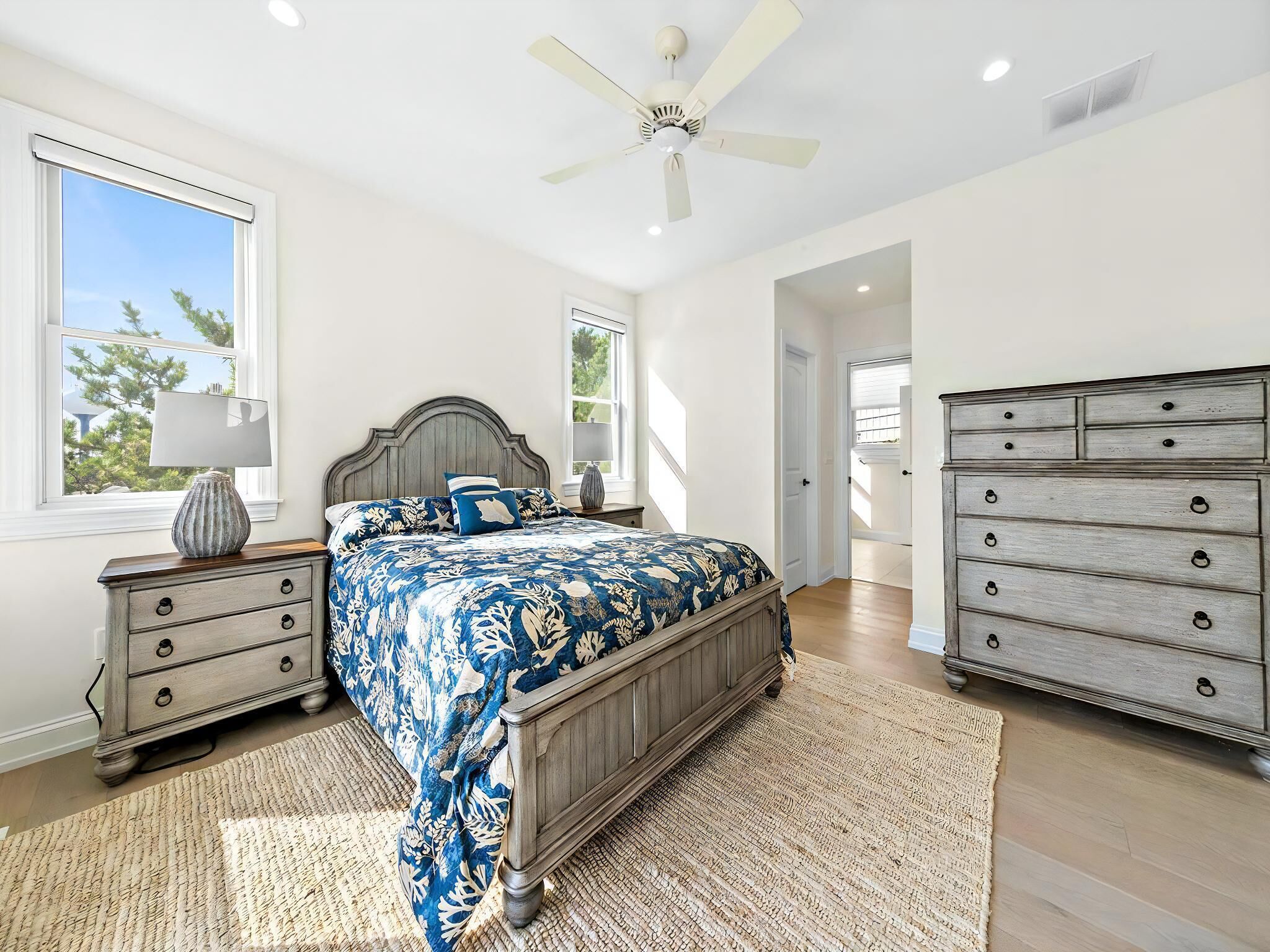 A bedroom with a bed, dresser, nightstands, and a ceiling fan.