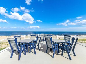 An outdoor seating area with tables and chairs overlooking the ocean.