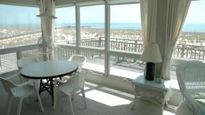 A balcony with a table and chairs, a fan, and a lamp.
