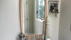 A teal console with a mirror, a 'LOVE' sign, a glass jar, and a white bottle. - 4 bedroom accommodation in Harvey Cedars (Harvey Cedars)