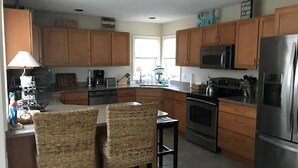 A kitchen with wooden cabinets, a stainless steel refrigerator, a microwave, and a coffee maker. - 4 bedroom accommodation in Harvey Cedars (Harvey Cedars)