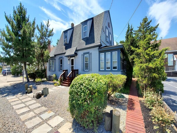 A two-story house with a front porch, a driveway, and a well-maintained garden.