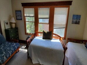 A bedroom with a bed, two bedside tables, a dresser, and a window with blinds.