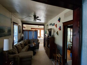 A living room with a sofa, a coffee table, a TV stand, and a ceiling fan.
