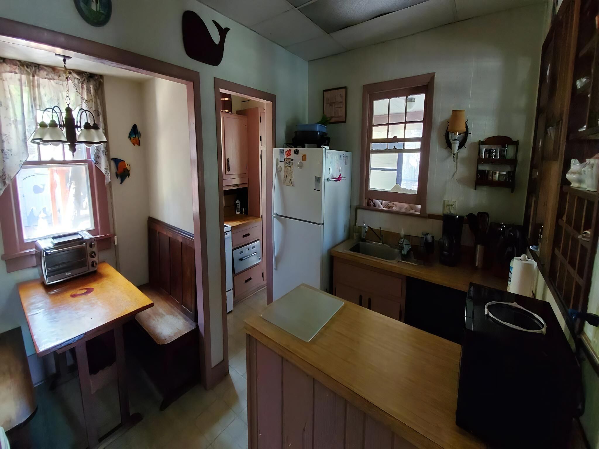 Eine kleine Küche mit Kühlschrank, Spüle, Fenster und einer Holzarbeitsplatte.