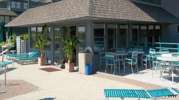 Un bâtiment doté d’un espace extérieur abrité, comprenant des tables et des chaises, des plantes en pot et une piscine.