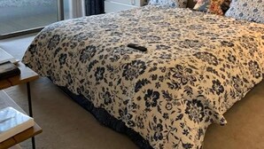 Une chambre avec un grand lit, une table de chevet, une lampe, un tableau au mur et une porte-fenêtre coulissante donnant sur un espace extérieur.