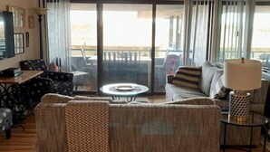 Un salon avec un canapé, une table basse et une lampe. Il y a un balcon avec vue.