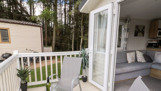A balcony with a glass table, two chairs, a bottle of wine, and a potted plant. - Daisy's Retreat (Morpeth)