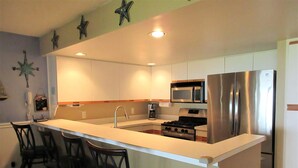 A modern kitchen with a central island, stainless steel appliances, and bar stools.