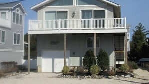 Ein zweistöckiges Haus mit Balkon, Garage und einem kleinen Garten.