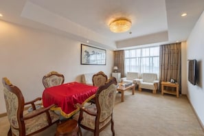 A hotel room with a dining table, chairs, a sofa, a TV, and a large window. - Huang Longshun Hotel (Xingguo)