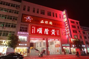 Un edificio con señalización iluminada, varias entradas y escaparate visible.
