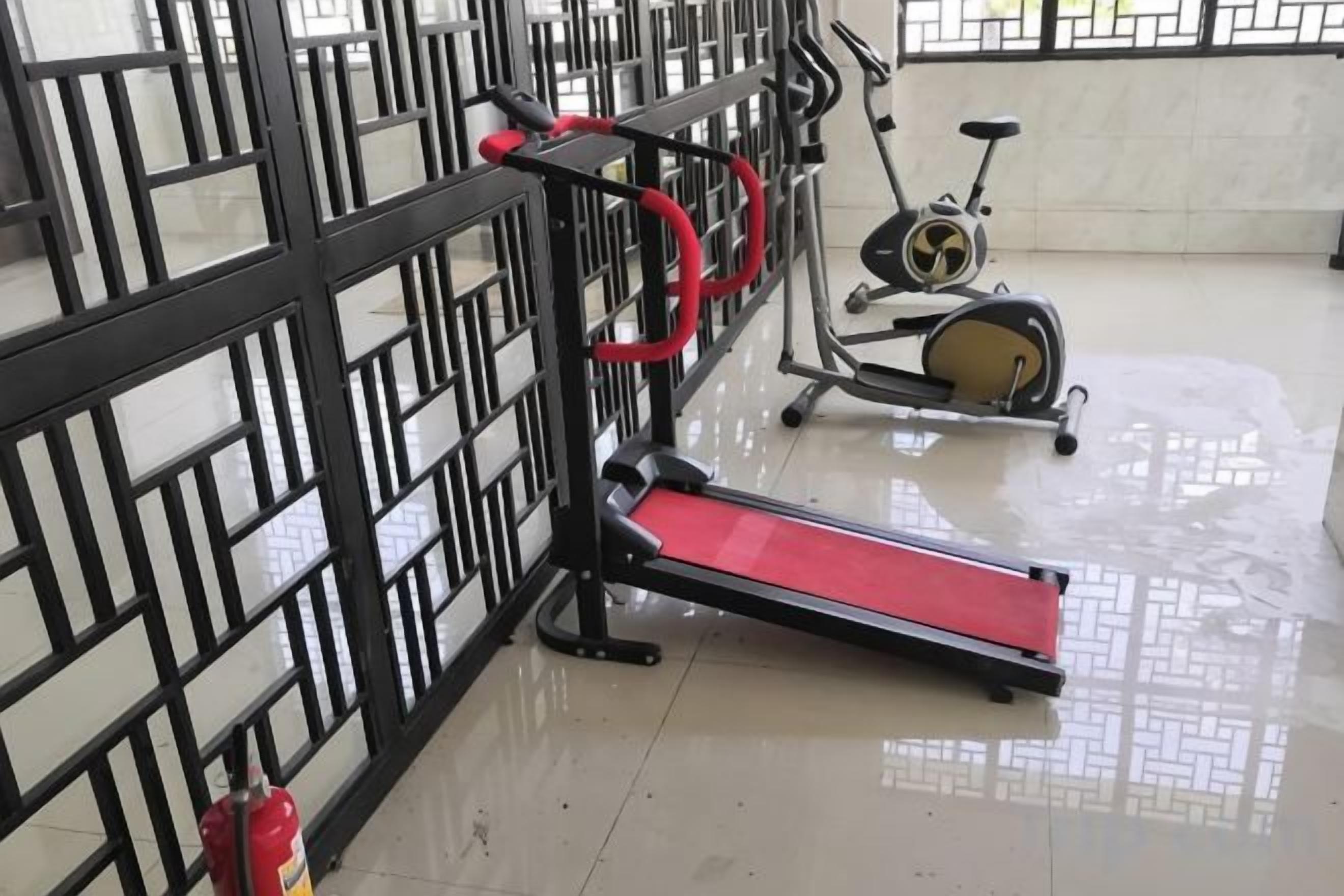 A gym with exercise equipment including a treadmill, stationary bike, and a red elliptical.
