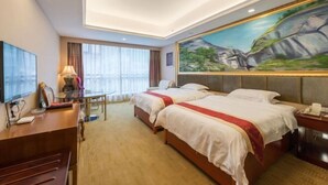 Une chambre d’hôtel avec deux lits, un bureau, une télévision et un tableau au mur.